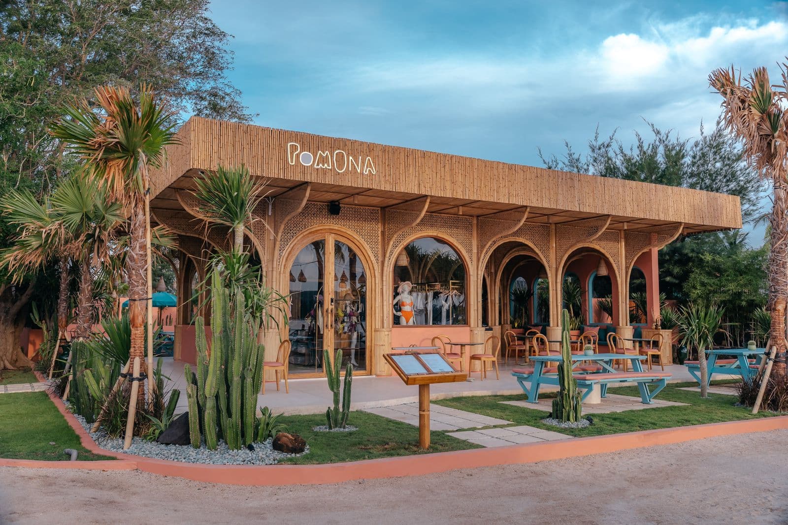The bamboo facade of Pomona with its neon sign, cacti and terrace tables
